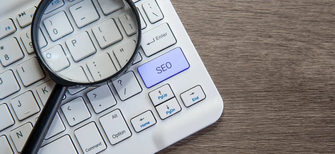 Magnifying glass highlights SEO key on keyboard, symbolizing WordPress SEO audit and optimization.