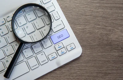 Magnifying glass highlights SEO key on keyboard, symbolizing WordPress SEO audit and optimization.